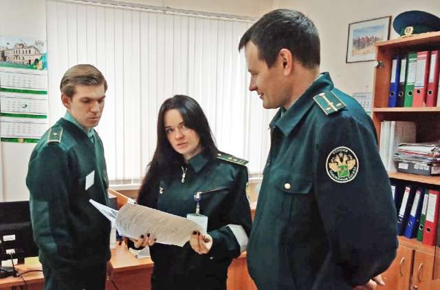 Сергей Баранов (справа) обсуждает с таможенными инспекторами план осмотра машин с грузами.