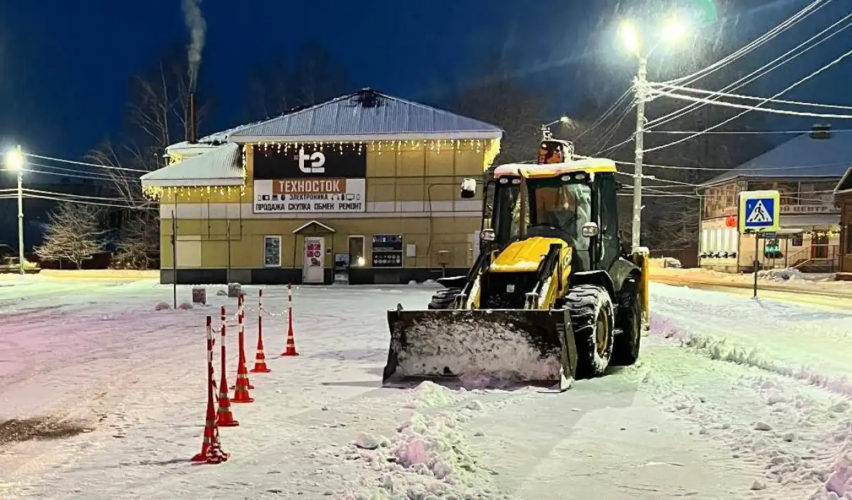 Водитель трактора чистил от снега территорию стоянки.