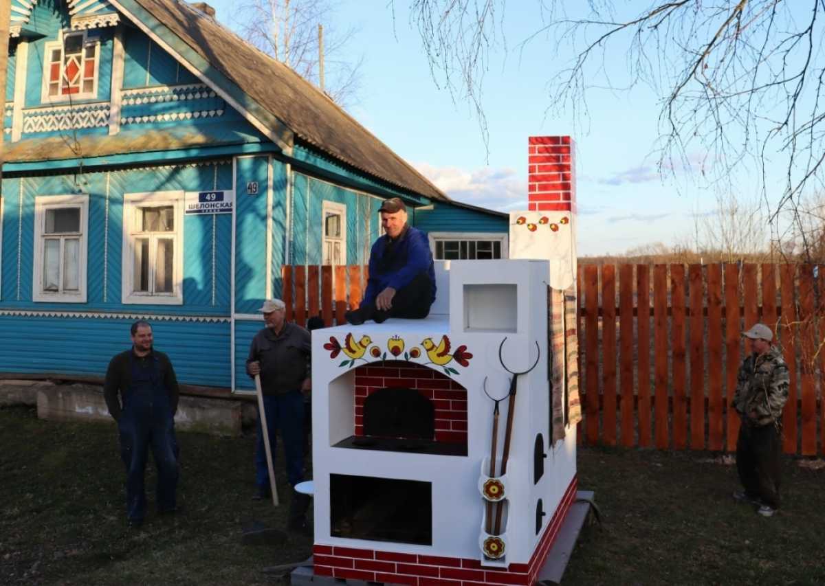 Белоснежная, в узорах, с самоваром, чугунками и ухватами, русская печка украсила общественную территорию около дороги.