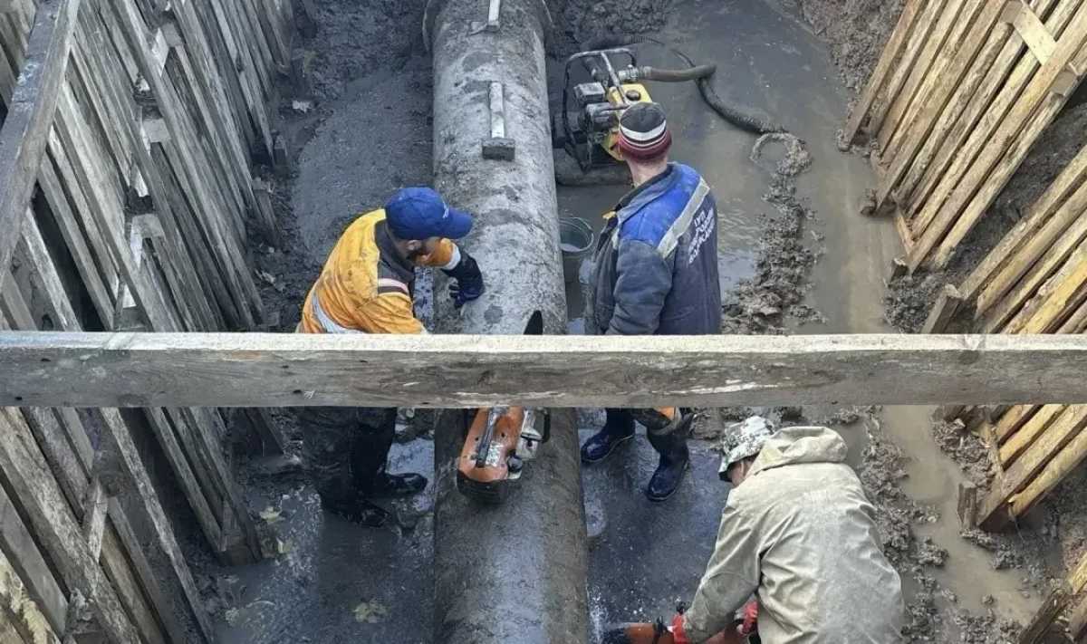 Рабочие занимаются врезкой новой линии системы водоснабжения в существующую сеть. Рабочие занимаются врезкой новой линии системы водоснабжения в существующую сеть.