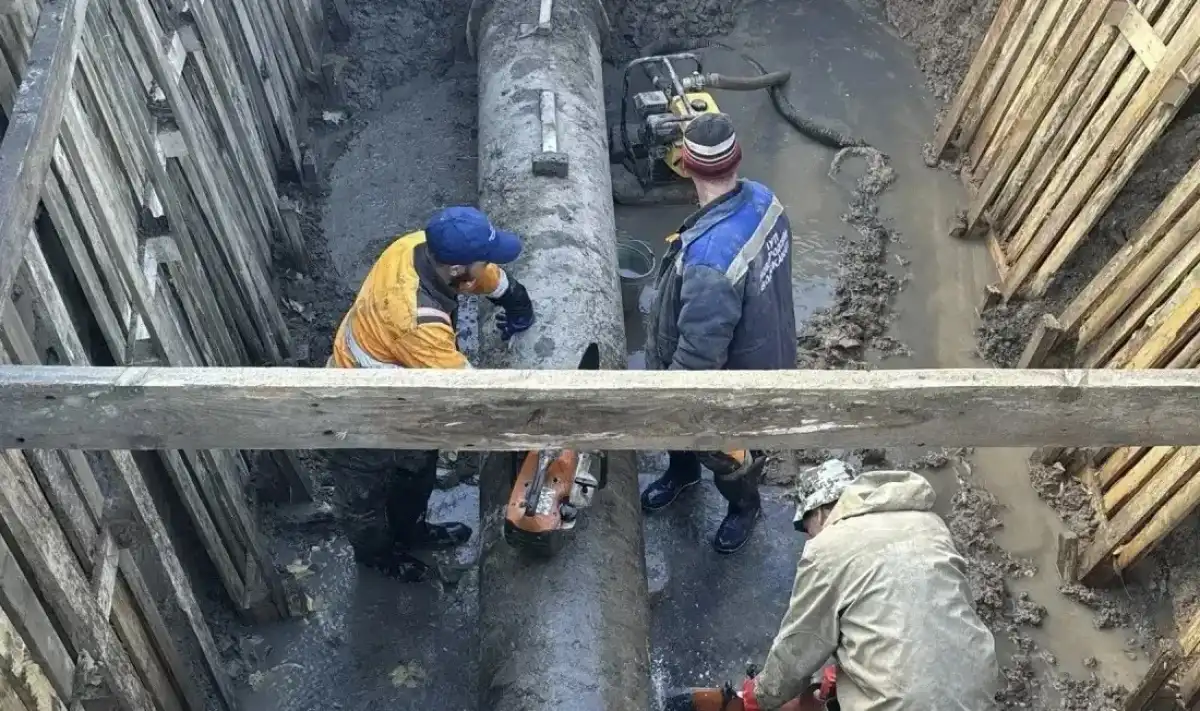 Рабочие занимаются врезкой новой линии системы водоснабжения в существующую сеть. Рабочие занимаются врезкой новой линии системы водоснабжения в существующую сеть.
